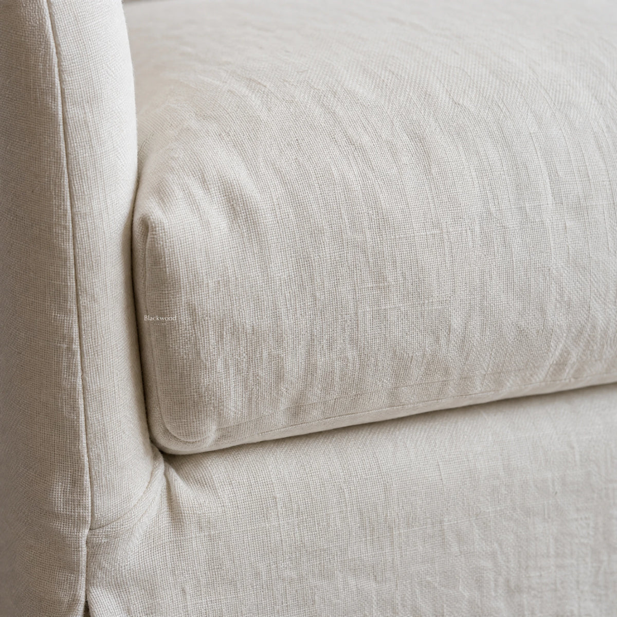 Close-up detail of the Monique Linen Slipcover Sofa showing soft curved arm and natural 100% linen texture.