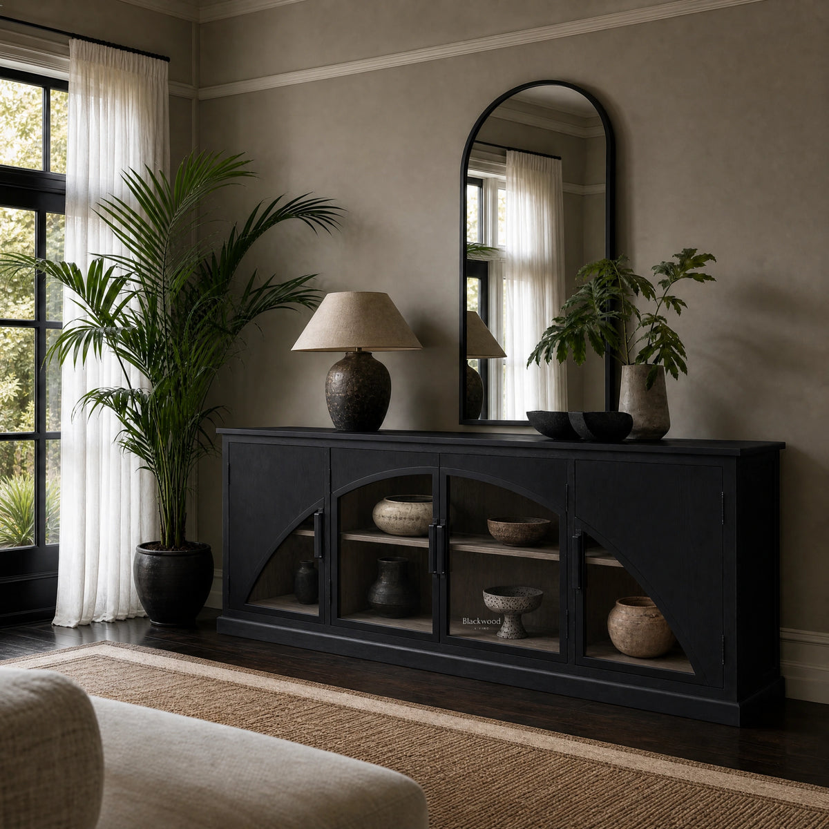 Black archway sideboard with sweeping arched glass doors, deep black finish, and warm timber interior displaying ceramic vessels.