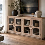 Light elm sideboard with glass doors and circular handles. Coastal style timber furniture styled with ceramics and a seascape painting.
