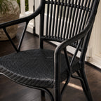 Black handmade rattan armchair featuring a finely braided seat, structured vertical backrest, and traditional wicker binding.