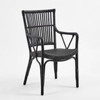 Black handmade rattan armchair featuring a braided seat, structured rattan-bar backrest, and armrests with traditional wicker binding.