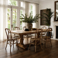 Sika Originals Lulu Rattan Side Chair arranged around a rustic wooden dining table in a sunlit room with French doors.