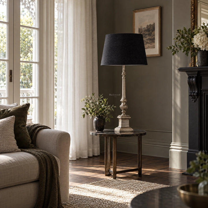 Tall table lamp with antique silver fluted stem and deep black cotton shade on a marble side table.