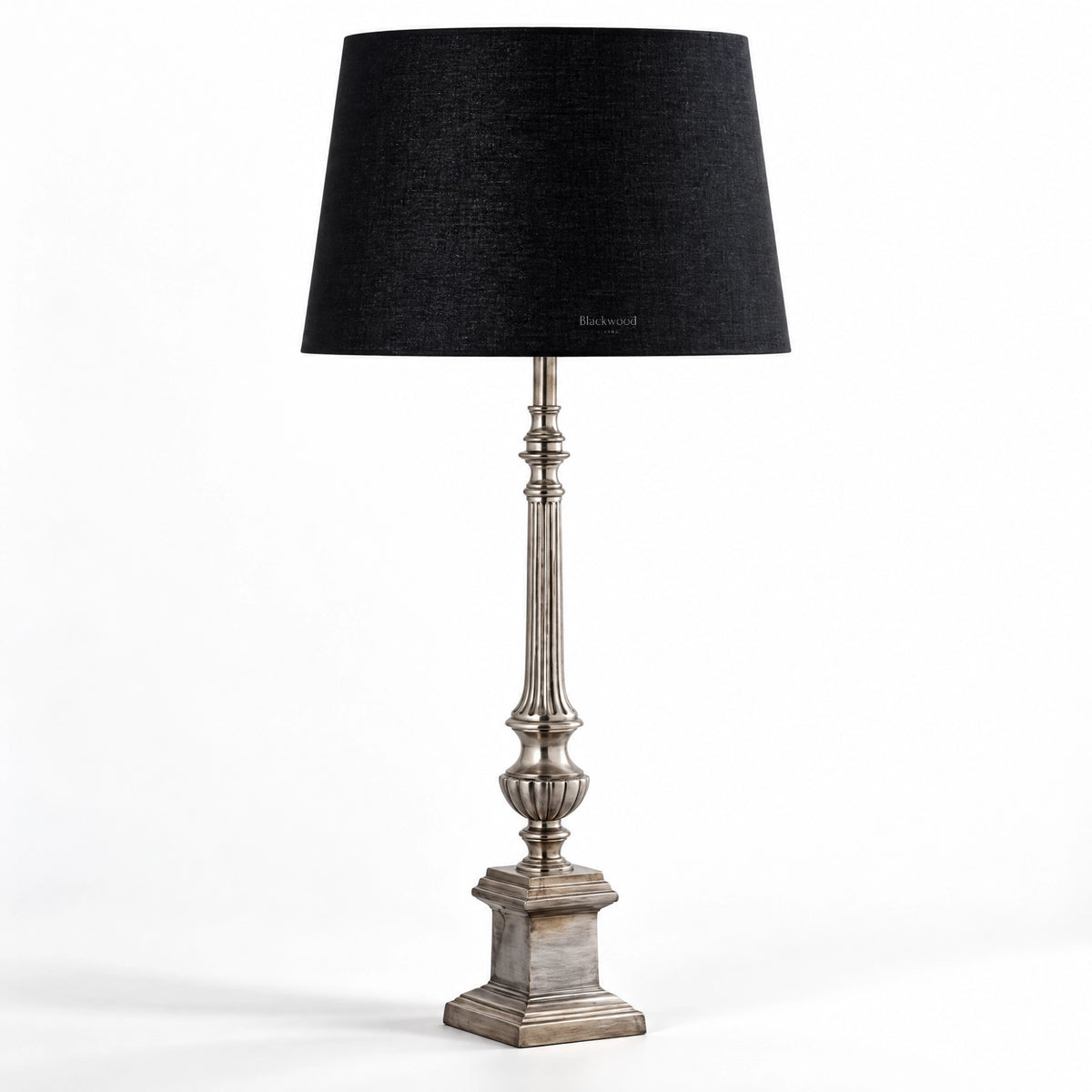 Tall table lamp with antique silver fluted stem, stepped pedestal base, and deep black cotton shade.