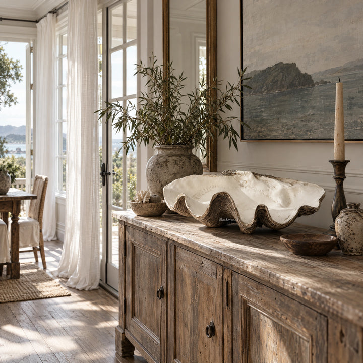 Large resin clam shell decor in warm ivory with earthy brown edges and undulating profile on a rustic wooden console table.