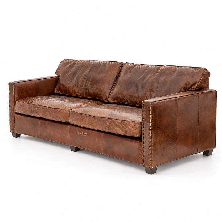 Brown leather 3-seat sofa with nailhead trim, thick cushions, and rustic character suitable for traditional living spaces.