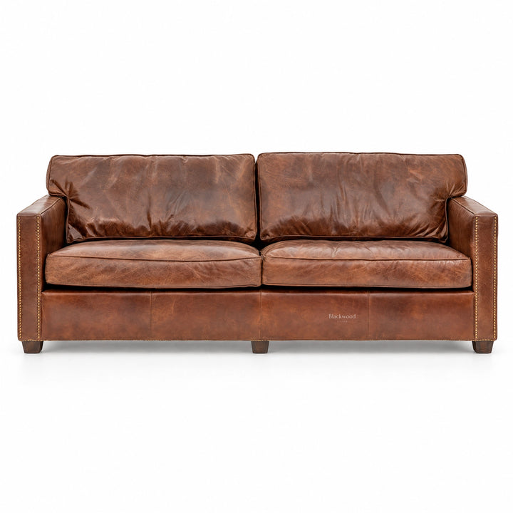 Brown leather 3-seat sofa with nailhead trim, featuring a distressed finish and plush cushions for a rustic, cozy aesthetic.