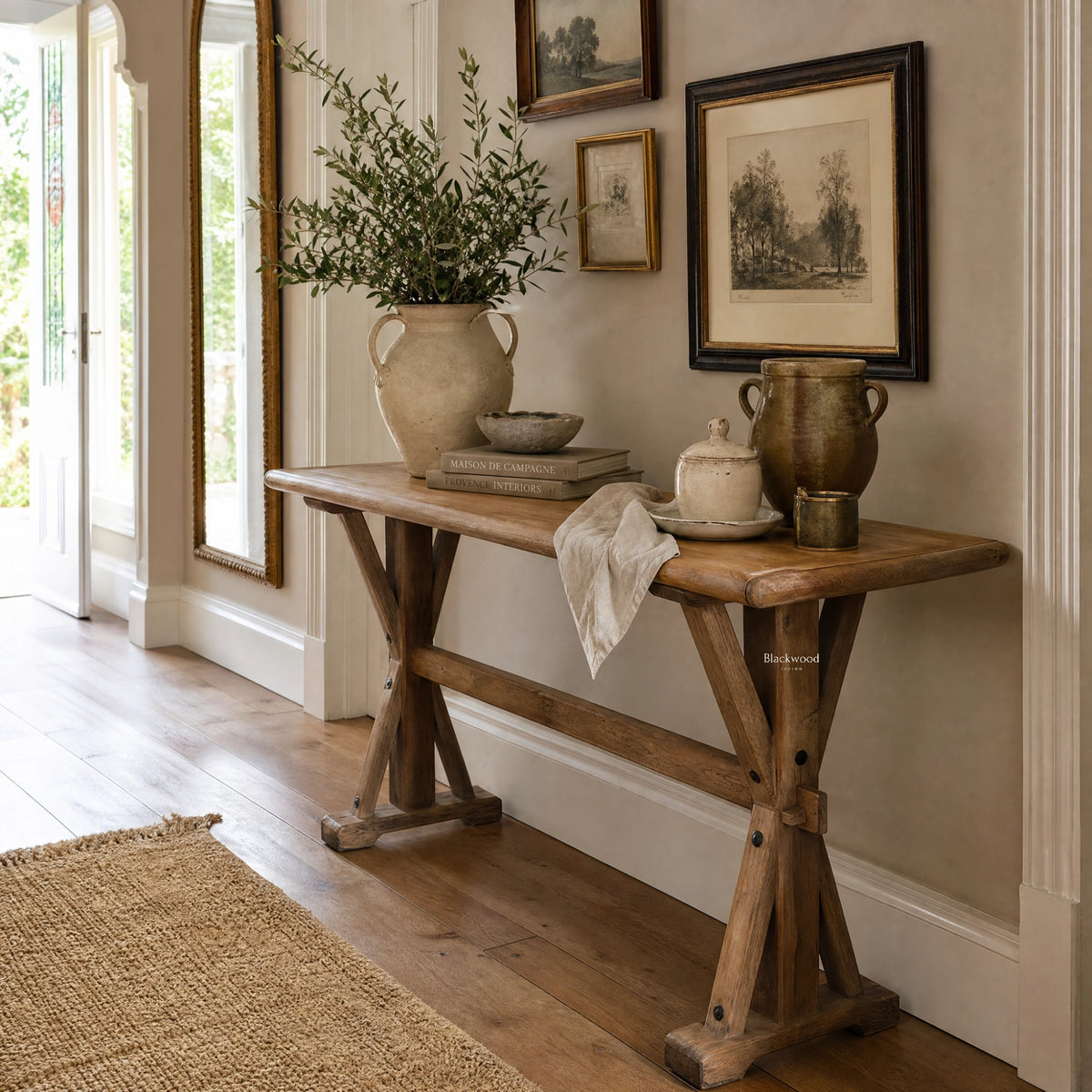Bastille Console in reclaimed elm with trestle base and rounded tabletop, styled with greenery and framed art.