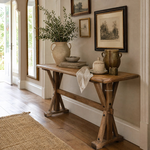 Bastille Console in reclaimed elm with trestle base and rounded tabletop, styled with greenery and framed art.