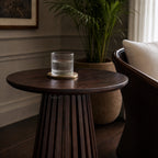 Banyan Side Table in cacao-stained solid oak with a slatted pedestal, styled in a living room.