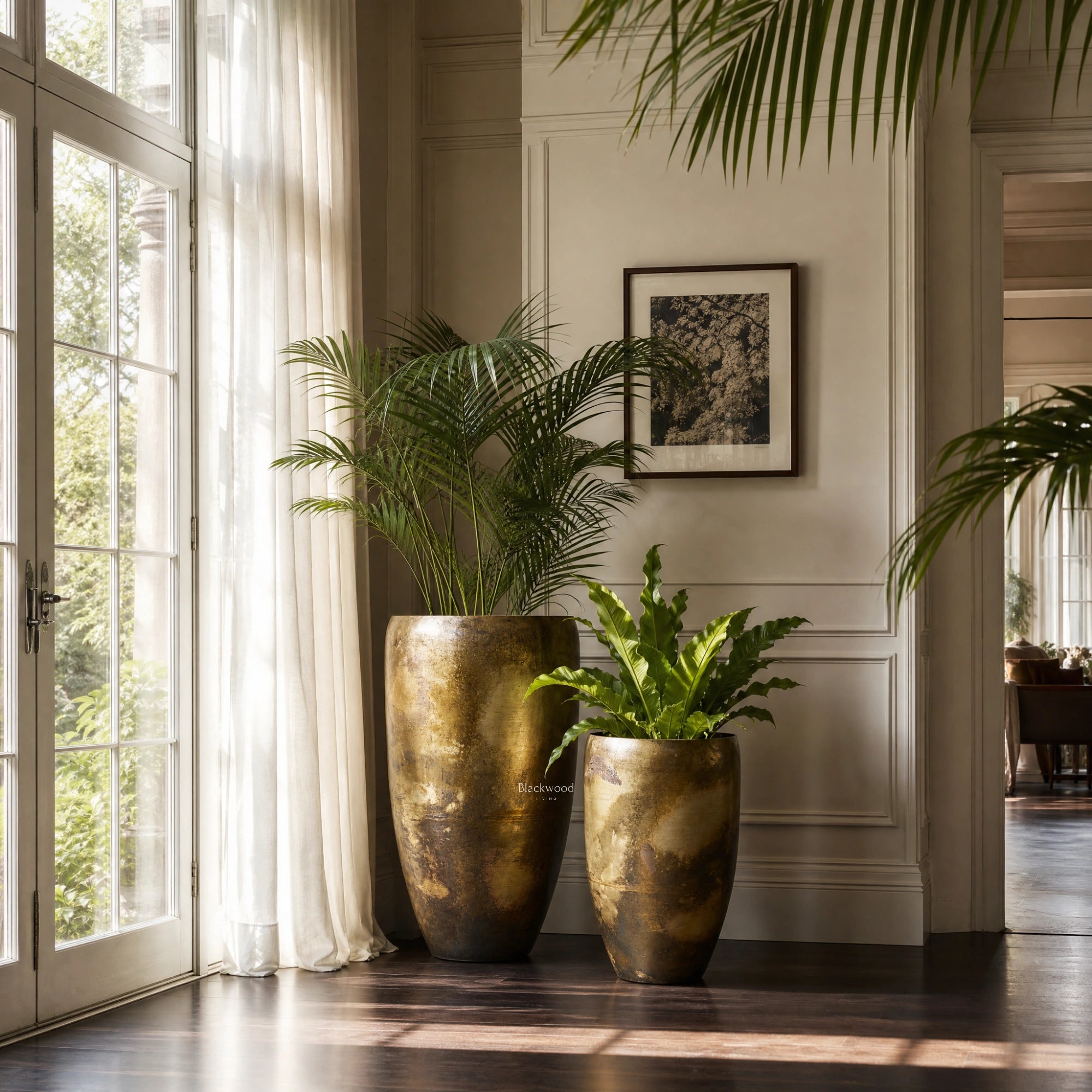 Nagar Planters Set/2, handcrafted iron in antiqued gold finish, with palm plants in a bright paneled room.
