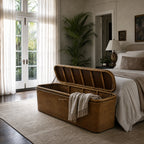 Tamarind Blanket Box at the foot of a bed, woven rattan storage in a sunlit plant-filled bedroom.