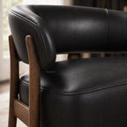 Black leather chair with curved back and solid ash timber frame, showcasing top grain texture and detailed stitching.