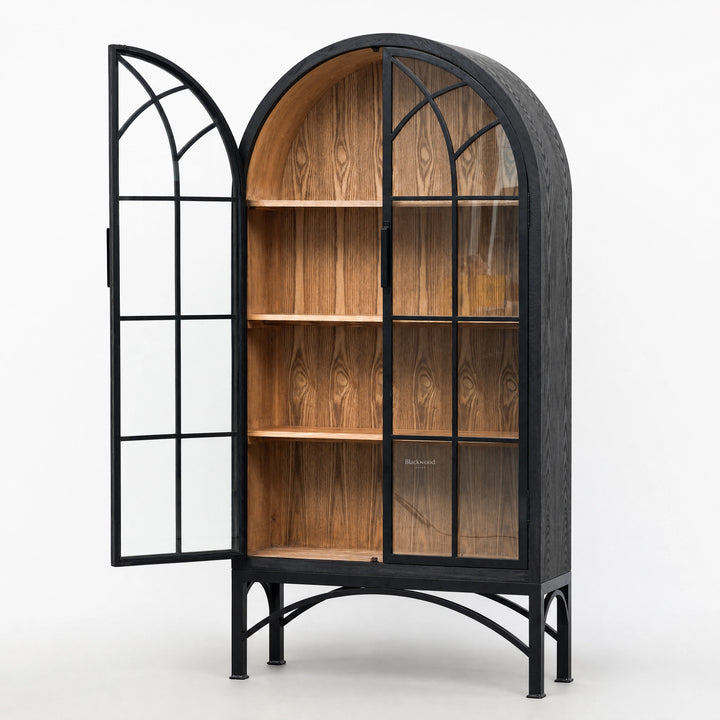 Tall arched display cabinet with black metal frame, glazed doors, and warm wood interior shelves on a metal base.