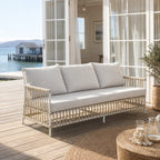 SIKA Exterior Caroline Sofa outdoors on a coastal deck with light cushions and a woven frame.