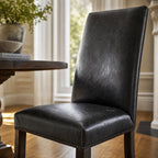 Manor Dining Chair with black South American top-grain leather and brass stud trim, on dark wood legs.