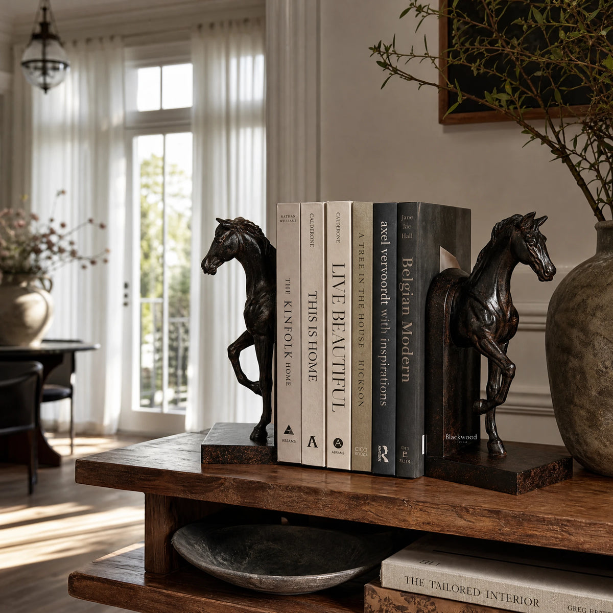 Equestrian Bookend Duo: two horse-shaped bookends flanking stacked books on a dark wooden shelf.