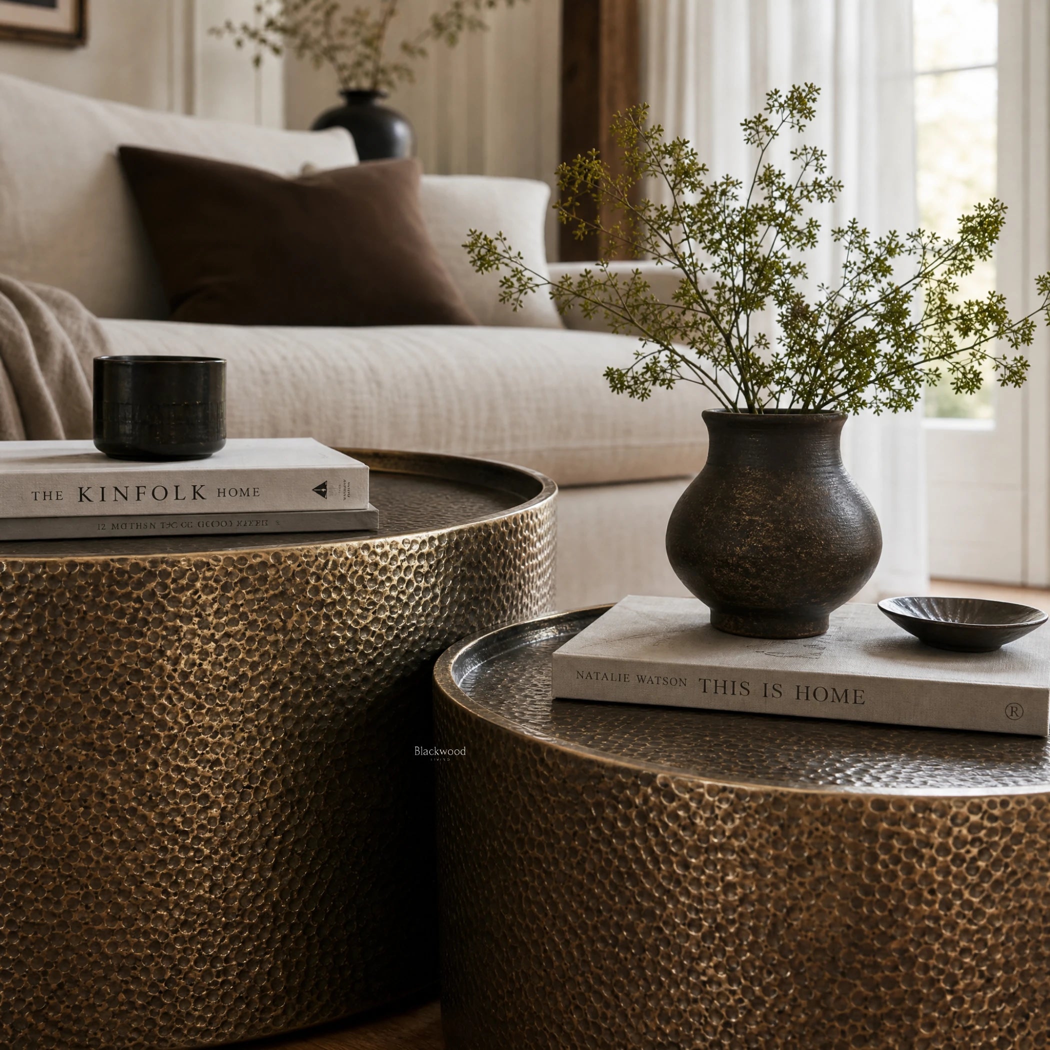 Foundry Table Duo in antique gold iron with hammered finish, catching light softly beside a plant and books.