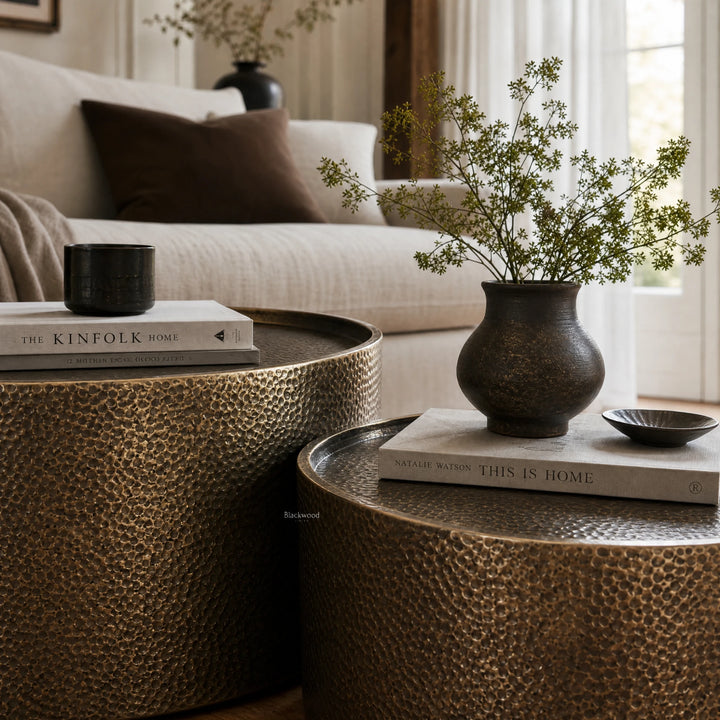 Foundry Table Duo in antique gold iron with hammered finish, catching light softly beside a plant and books.