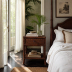 Plantation 1 Drawer Bedside table in handcrafted rattan with woven detailing and storage beside a bed.