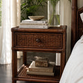 Plantation 1 Drawer Bedside with woven rattan, featuring a ceramic bowl atop stacked books and a glass vase of greenery.