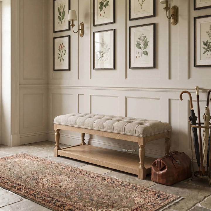 Oakfield Bench with tufted upholstery and sculpted oak frame set against paneled walls with botanical prints.