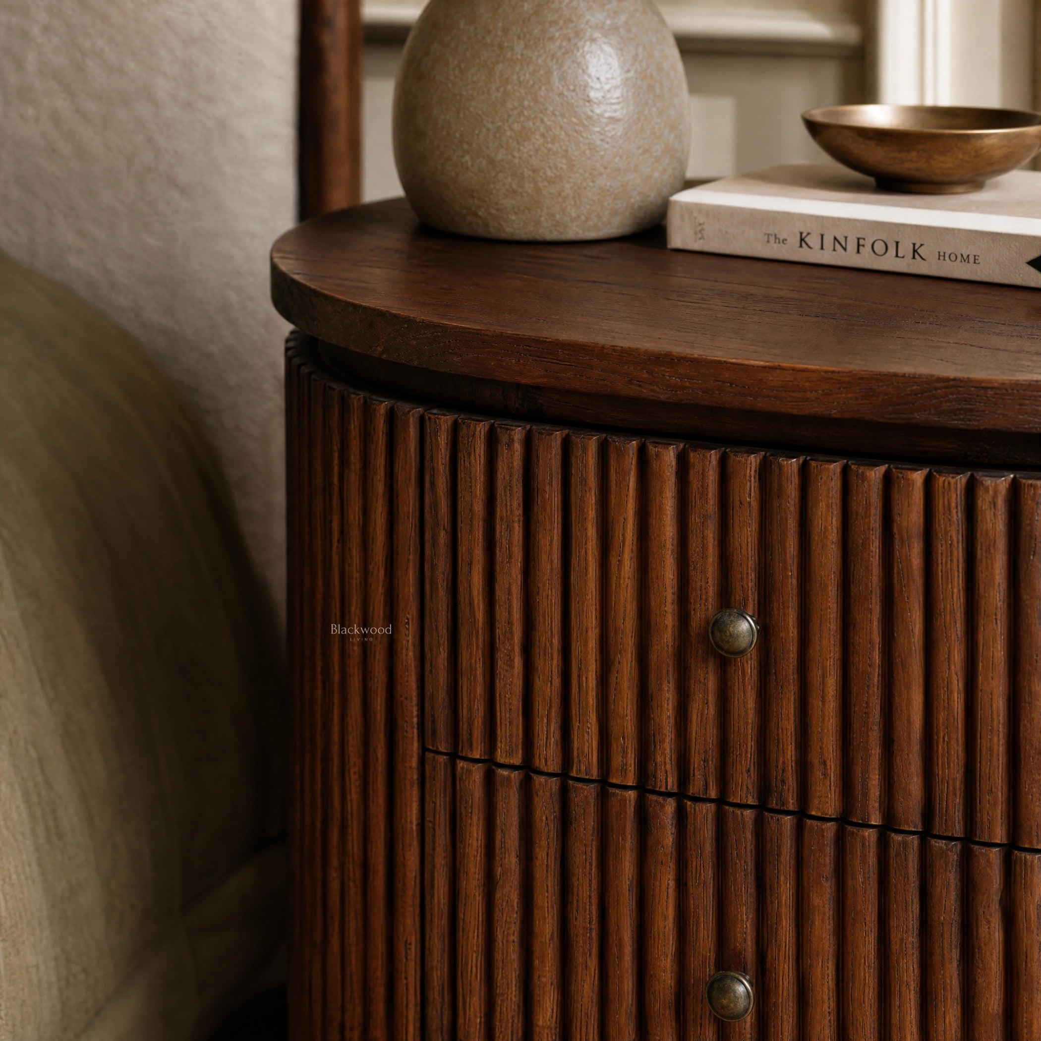 Reed Bedside Table in old elm with rounded silhouette and fluted timber detailing, paired with a vase and brass bowl.