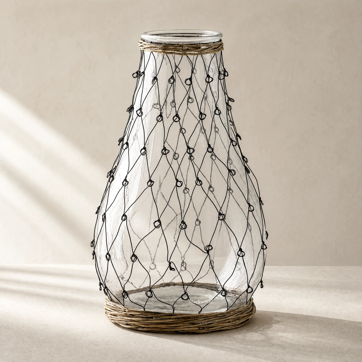 Tide Wire Glass Vase featuring clear glass with hand-wrapped wire mesh and natural wicker base.