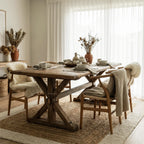Foundry Dining Table in a sunlit room with wooden chairs, sheepskin throws, and tableware, crafted from recycled elm.
