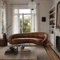 Pure Jane Leather Sofa curved in rich buffalo leather, hand-colored in Italy, crafted in Romania, in a living room.