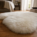 Ivory single sheepskin rug, genuine New Zealand wool, laid on hardwood floor in a cozy bedroom.