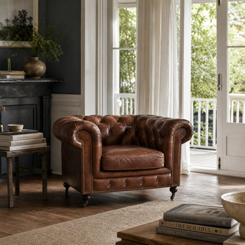 Ashcroft Armchair - Vintage Tobacco leather, deep button tufted Chesterfield in a cozy living room.