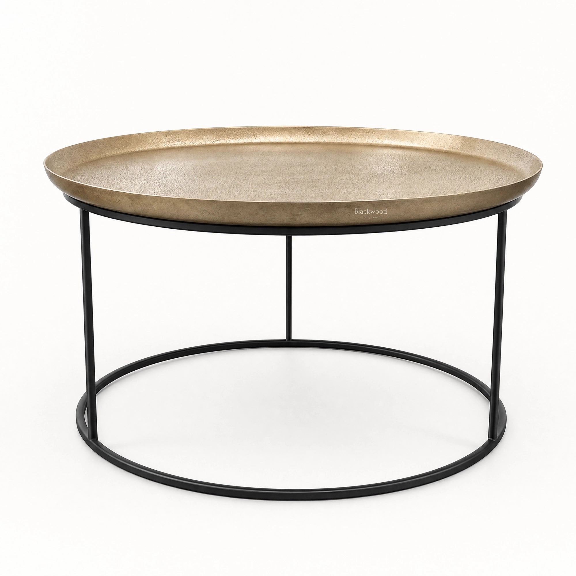 Round antique brass coffee table with raised tray edge and slender black iron frame for plantation-inspired interiors.