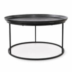 Round antique black coffee table with raised tray-style aluminium top and slender iron frame base for plantation-inspired interiors.