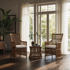 DaVinci rattan armchairs with high backs and white cushions flank a matching side table in a sunlit room with sheer curtains.