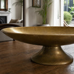 Malabar Centrepiece aluminium pedestal bowl with vintage brass finish on wooden table