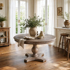 Laurent Dining Table made of reclaimed elm with a pedestal base in a bright sunlit dining room.